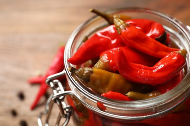 Glass jar with pickled peppers on table, closeup