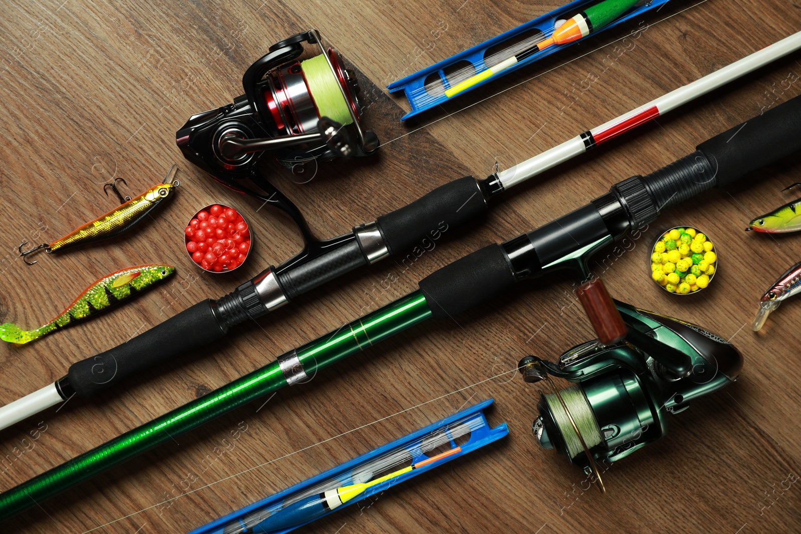 Photo of Spinning rods and fishing tackle on wooden background, above view, flat lay