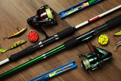 Photo of Spinning rods and fishing tackle on wooden background, above view, flat lay