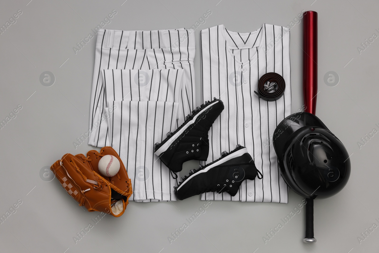 Photo of Baseball uniform and other sports equipment on white background, flat lay