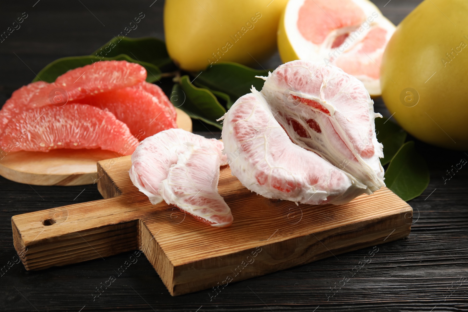 Photo of Fresh peeled pomelo fruit on black wooden table, closeup