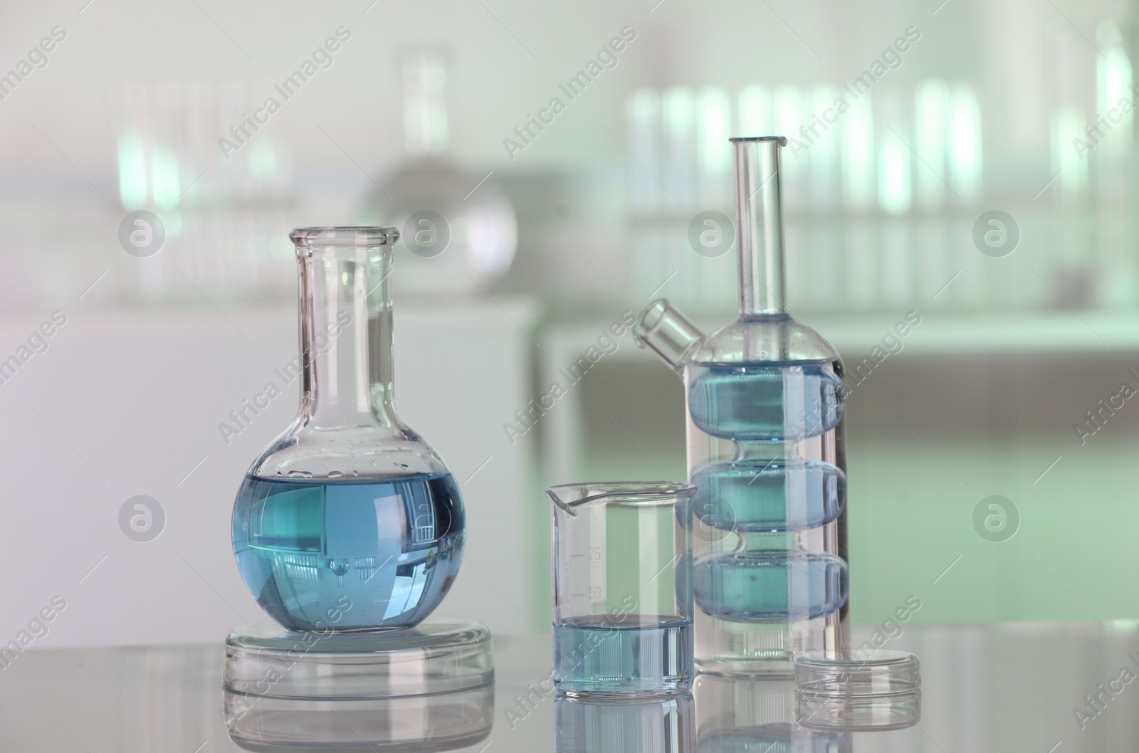 Photo of Laboratory analysis. Different glassware with liquid on white table against blurred background