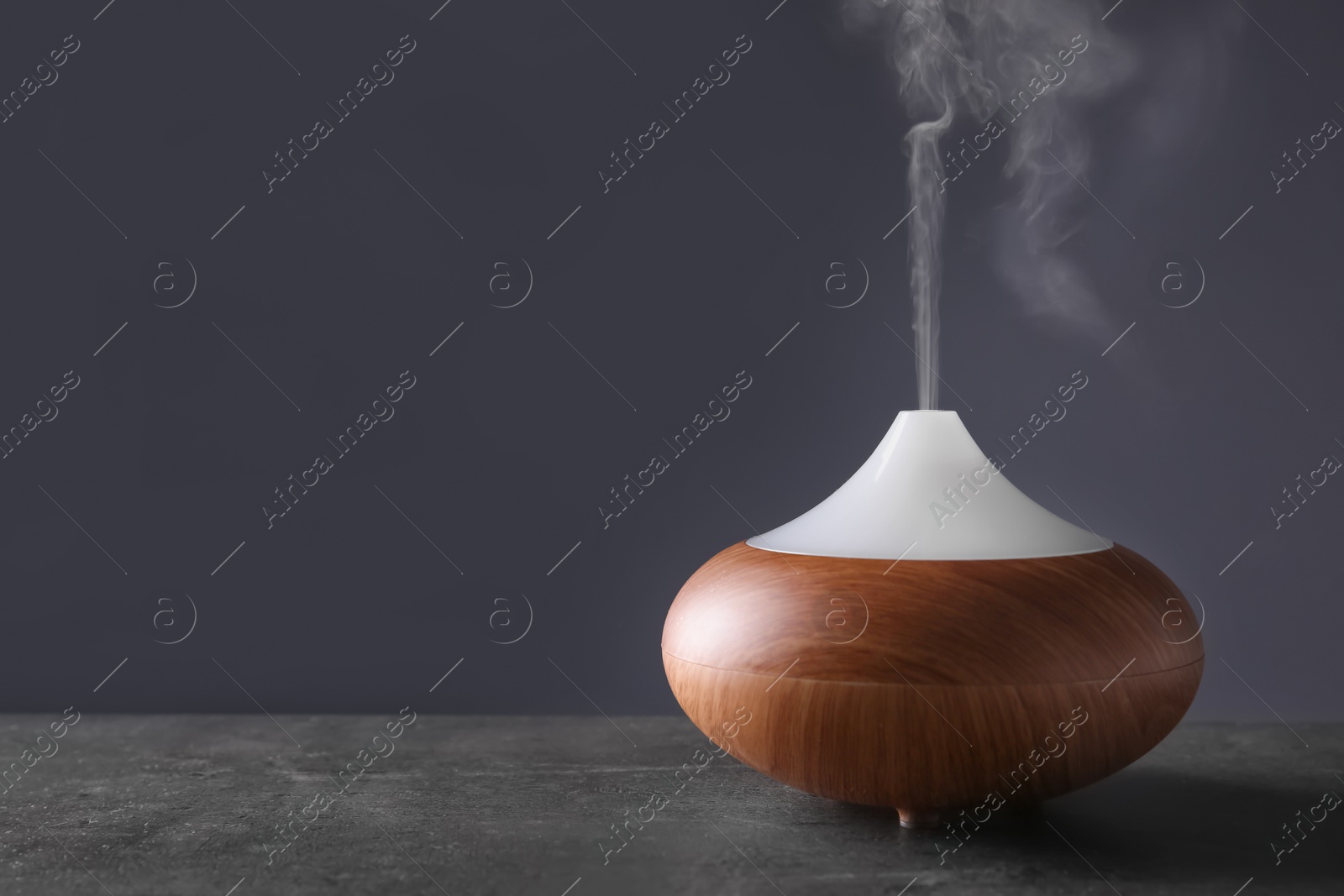 Photo of Aroma oil diffuser on table against color background