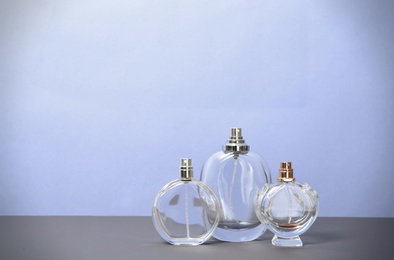 Different perfume bottles on table against color background