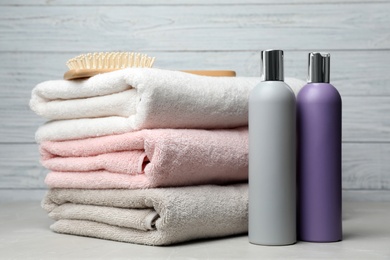 Photo of Towels with hair brush and shampoo bottles on table