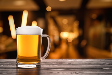 Image of Fresh cold beer on wooden table in pub, space for text