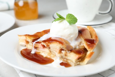 Slice of traditional apple pie with ice cream on plate, closeup
