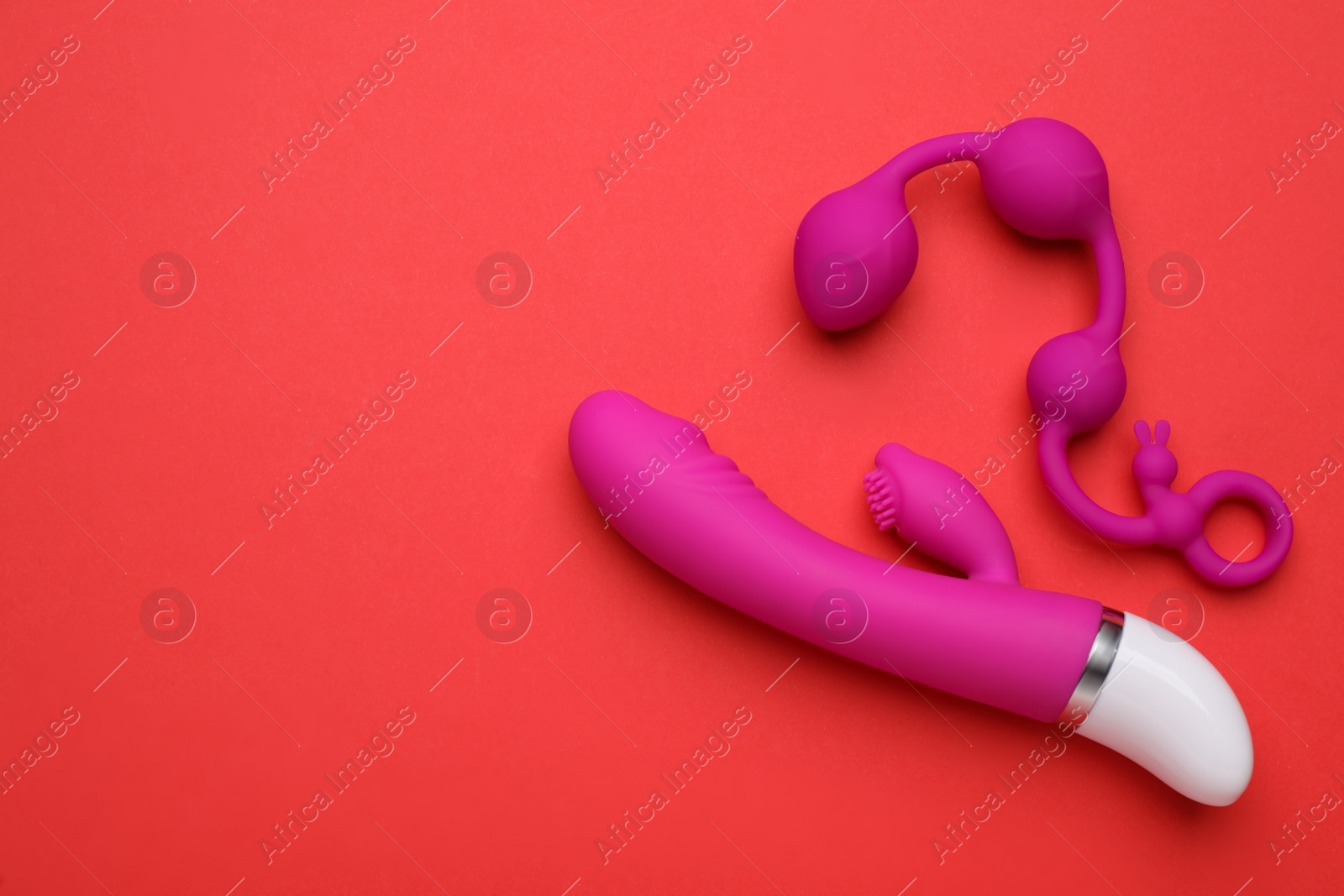 Photo of Pink sex toys on red background, flat lay. Space for text