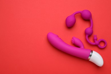 Pink sex toys on red background, flat lay. Space for text