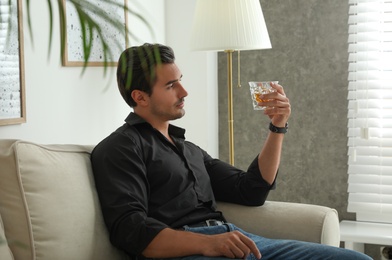 Young man with glass of whiskey at home