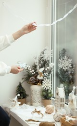 Woman decorating room for Christmas near window, closeup