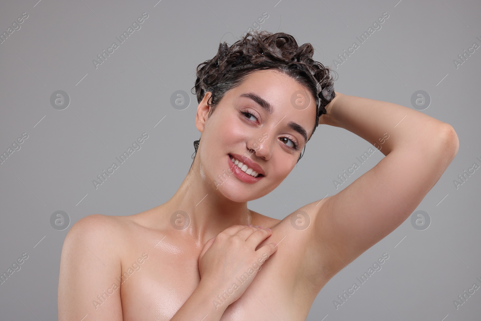 Photo of Portrait of beautiful happy woman washing hair on grey background