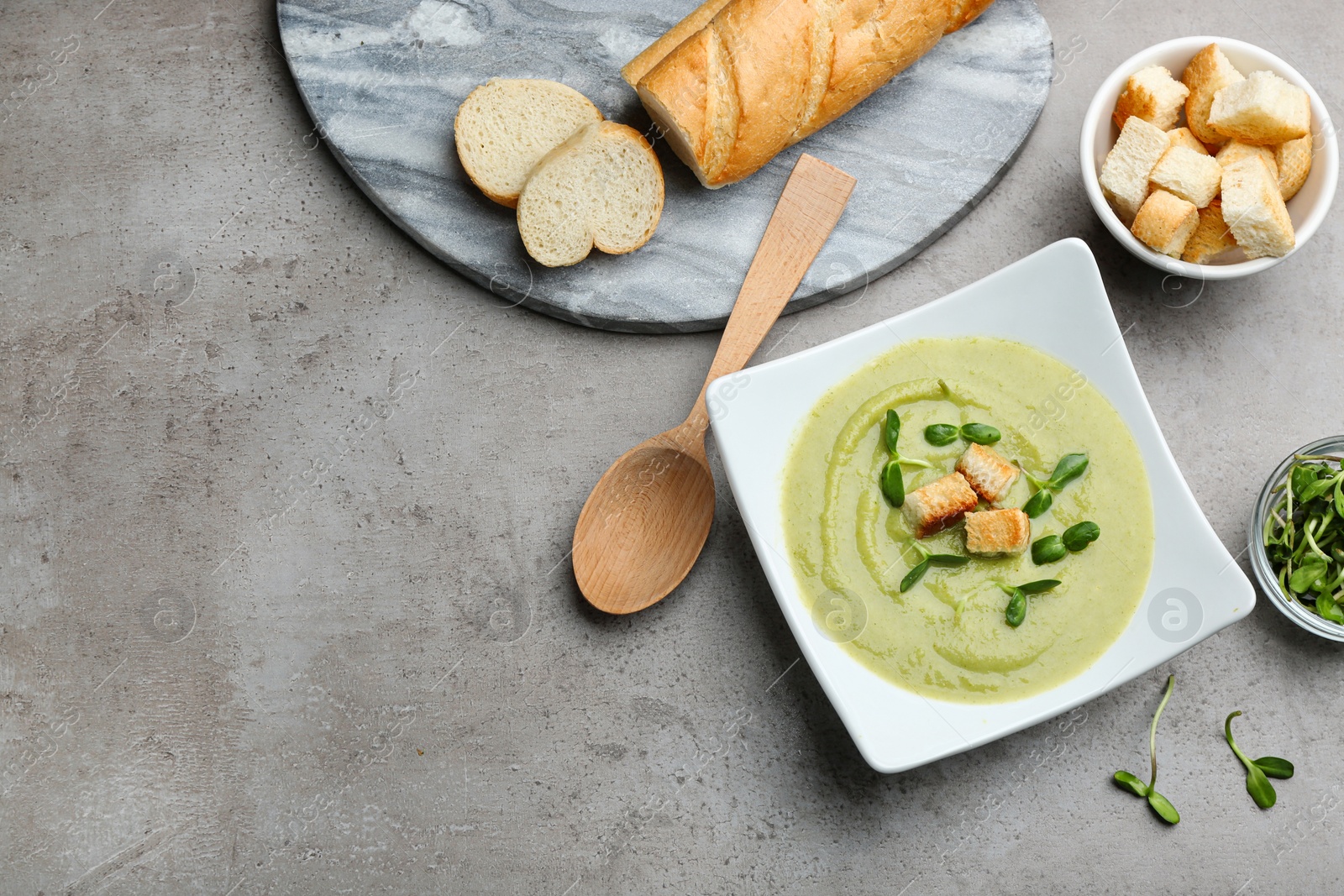 Photo of Flat lay composition with bowl of broccoli cream soup on grey table, space for text