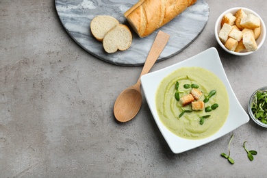 Photo of Flat lay composition with bowl of broccoli cream soup on grey table, space for text