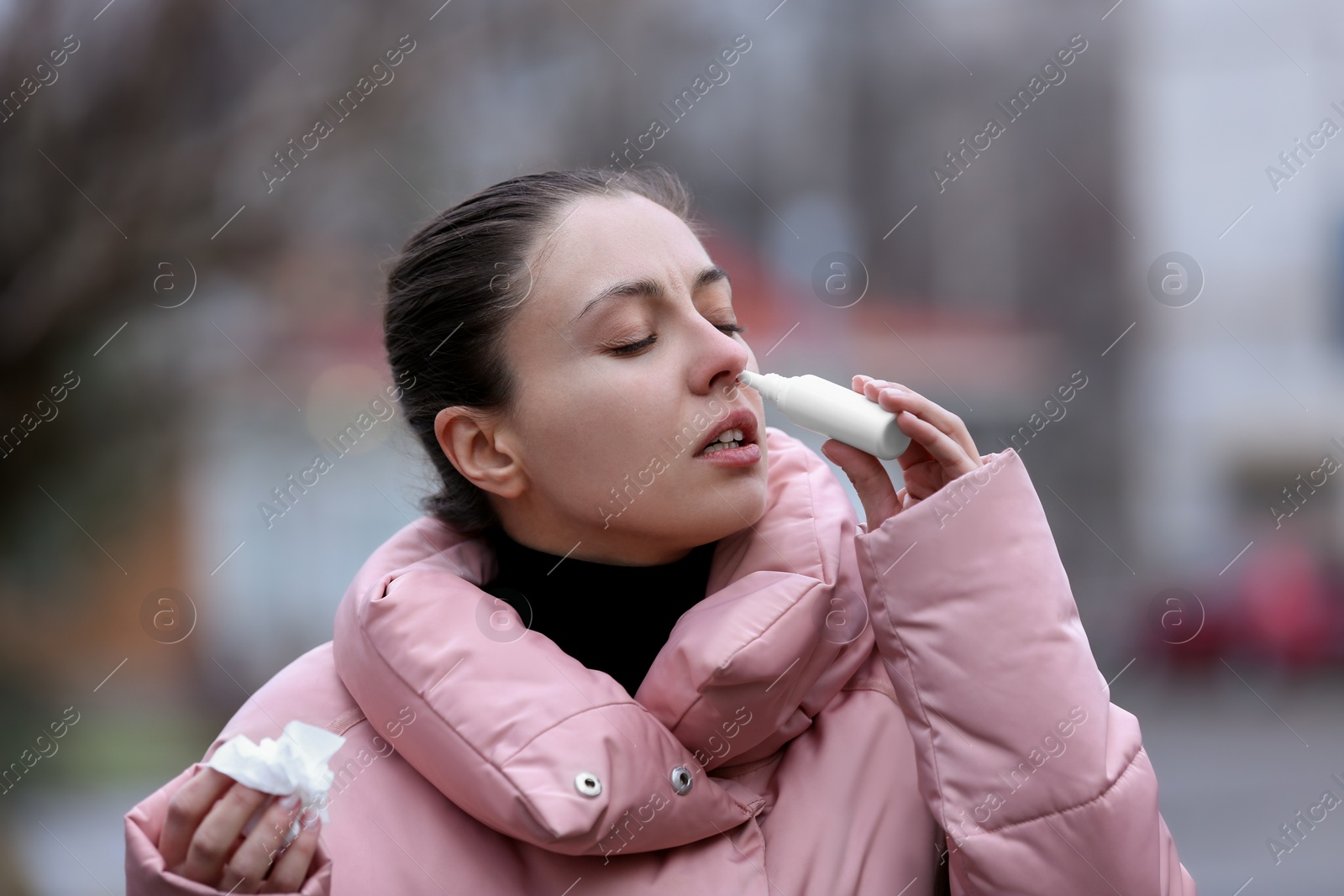 Photo of Ill woman using nasal spray on street