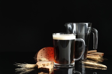 Delicious kvass, bread and spikes on black background. Space for text