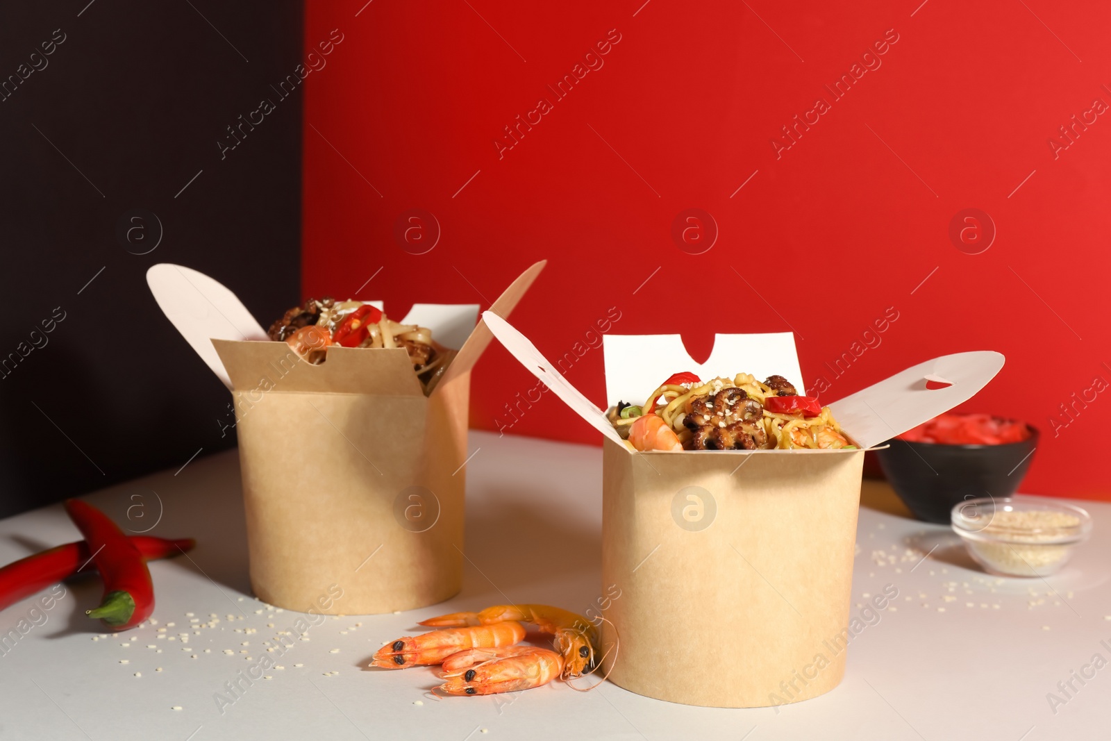 Photo of Boxes of wok noodles with seafood on color background
