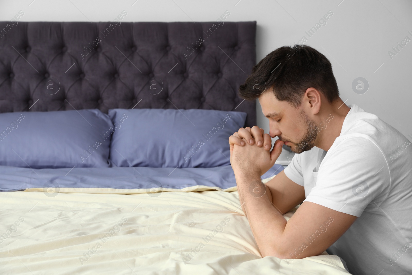 Photo of Handsome man saying bedtime prayer at home. Space for text