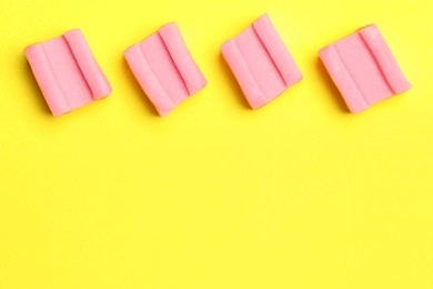 Pink bubble gums on yellow background, flat lay. Space for text