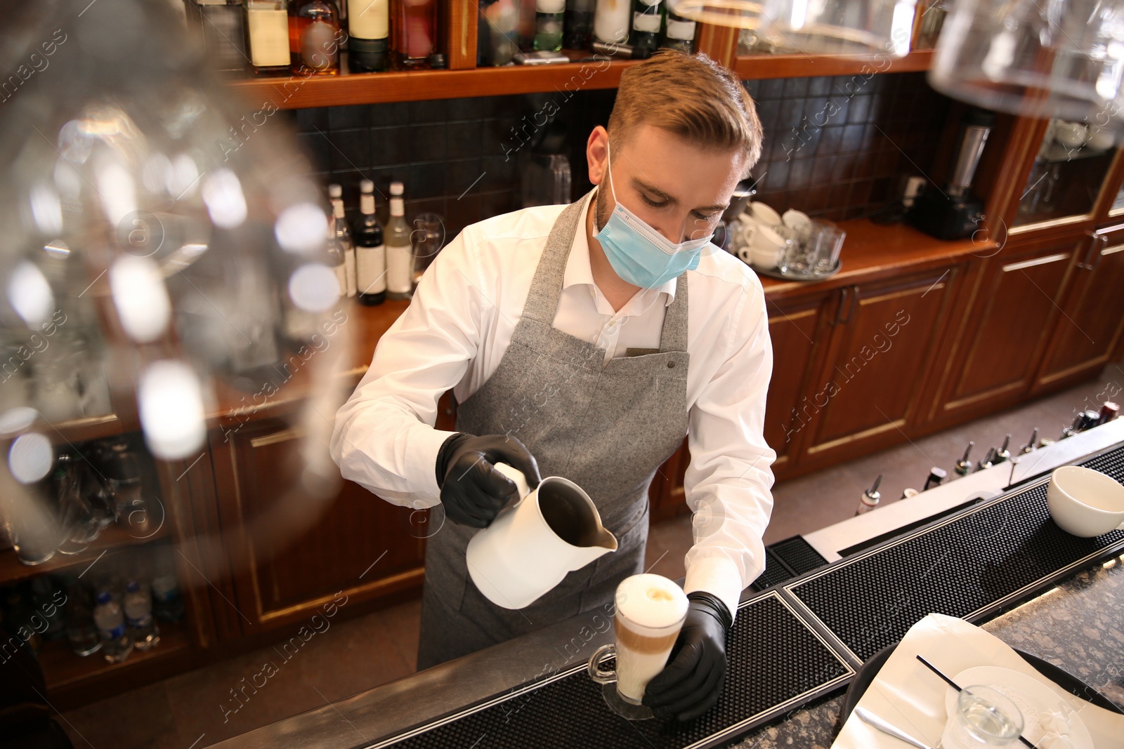 Photo of Barista preparing coffee at counter in restaurant. Catering during coronavirus quarantine
