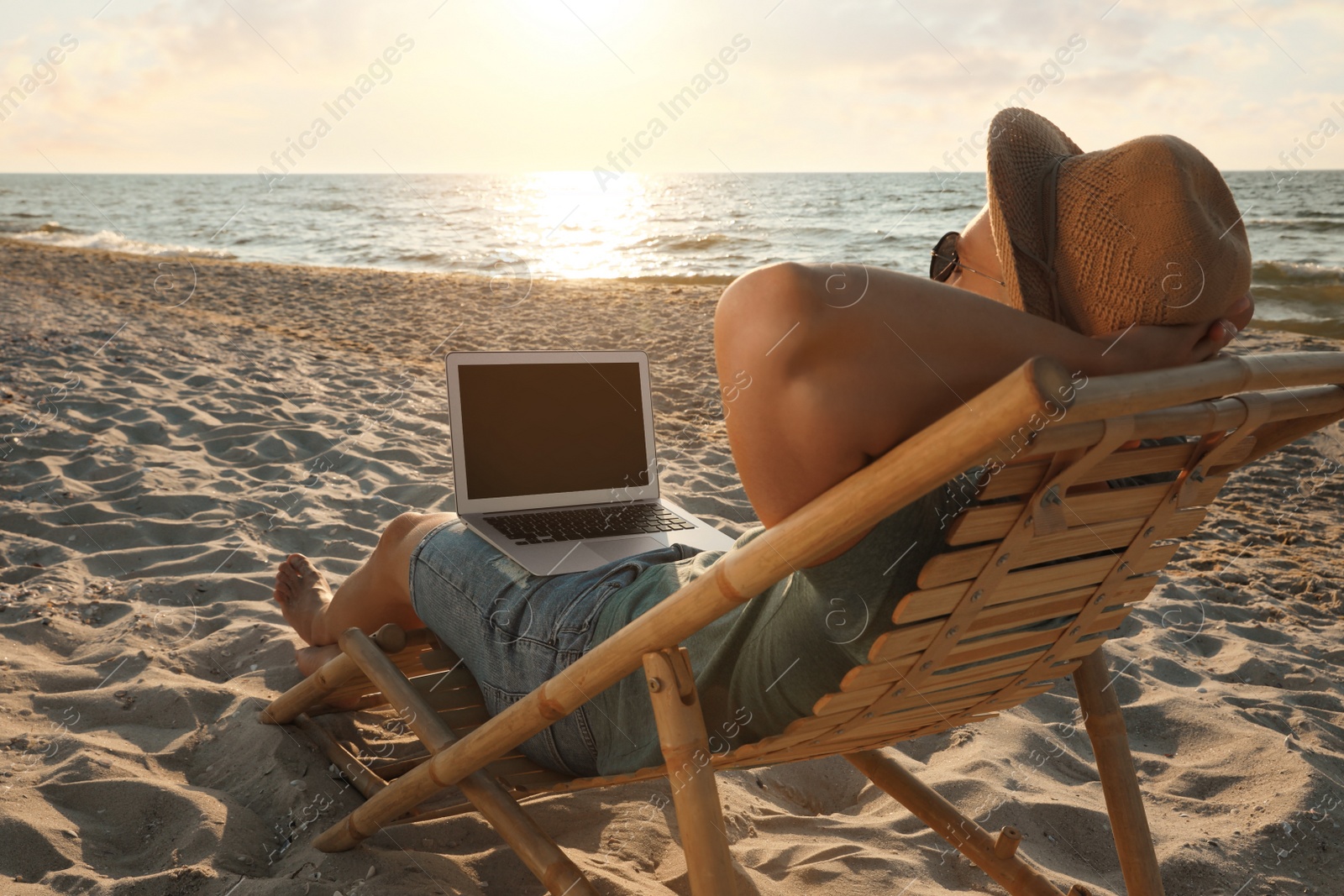 Photo of Man with laptop relaxing in deck chair on beach