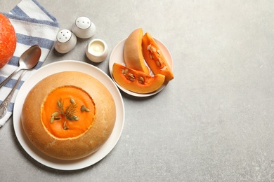 Flat lay composition with pumpkin soup served in bread and space for text on table