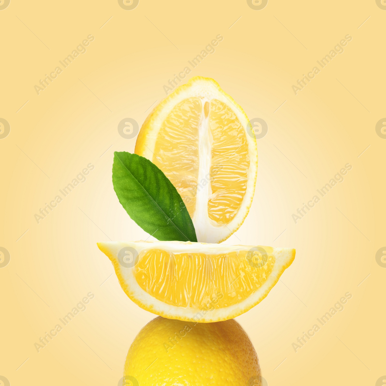 Image of Stack of fresh lemons with green leaf on pastel gold background
