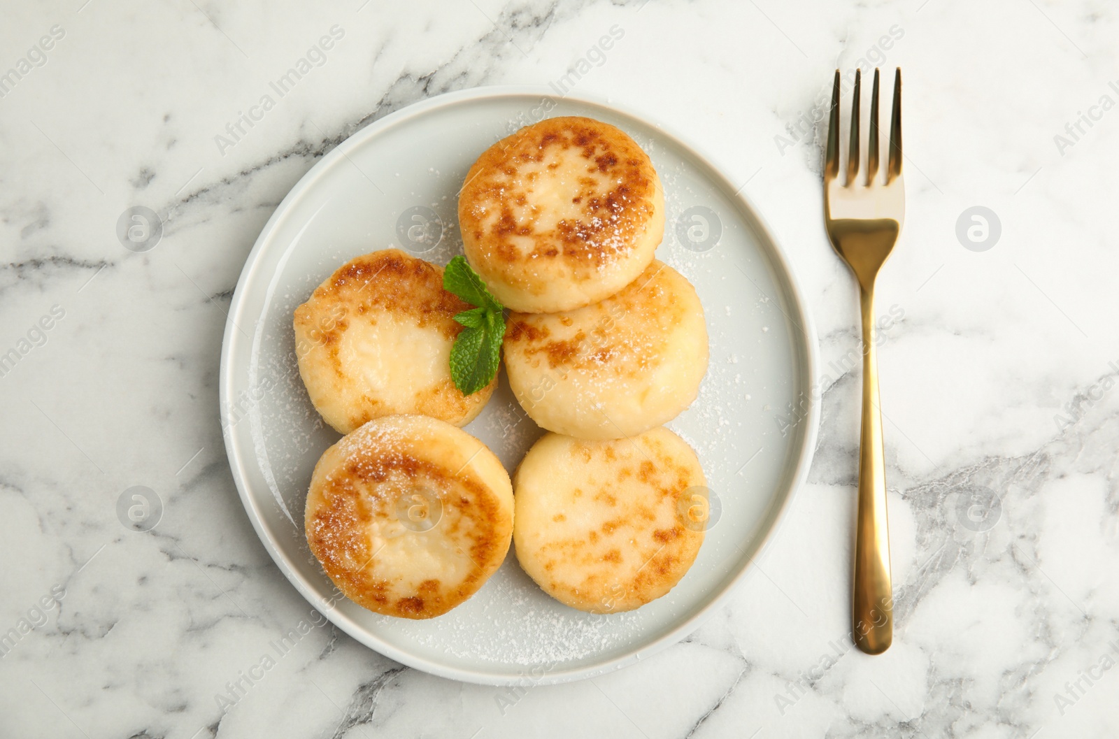 Photo of Delicious cottage cheese pancakes with mint and icing sugar on white marble table, flat lay