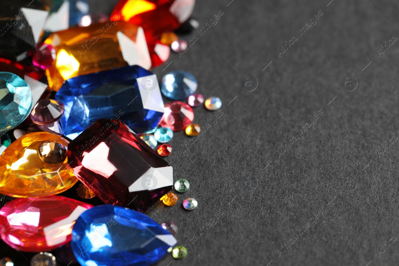 Photo of Beautiful gemstones for jewelry on dark background, closeup. Space for text