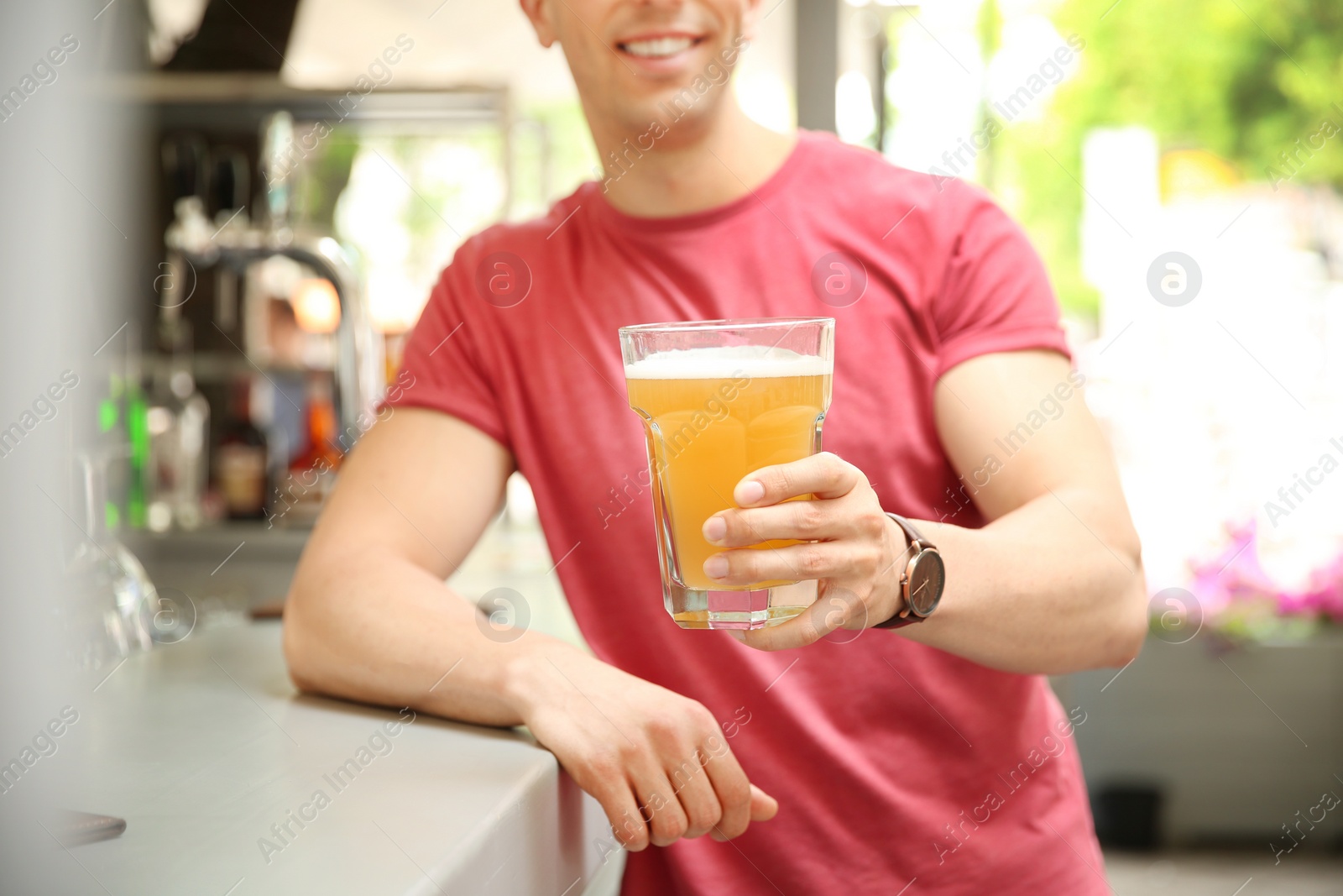 Photo of Young man with glass of cold beer near bar counter