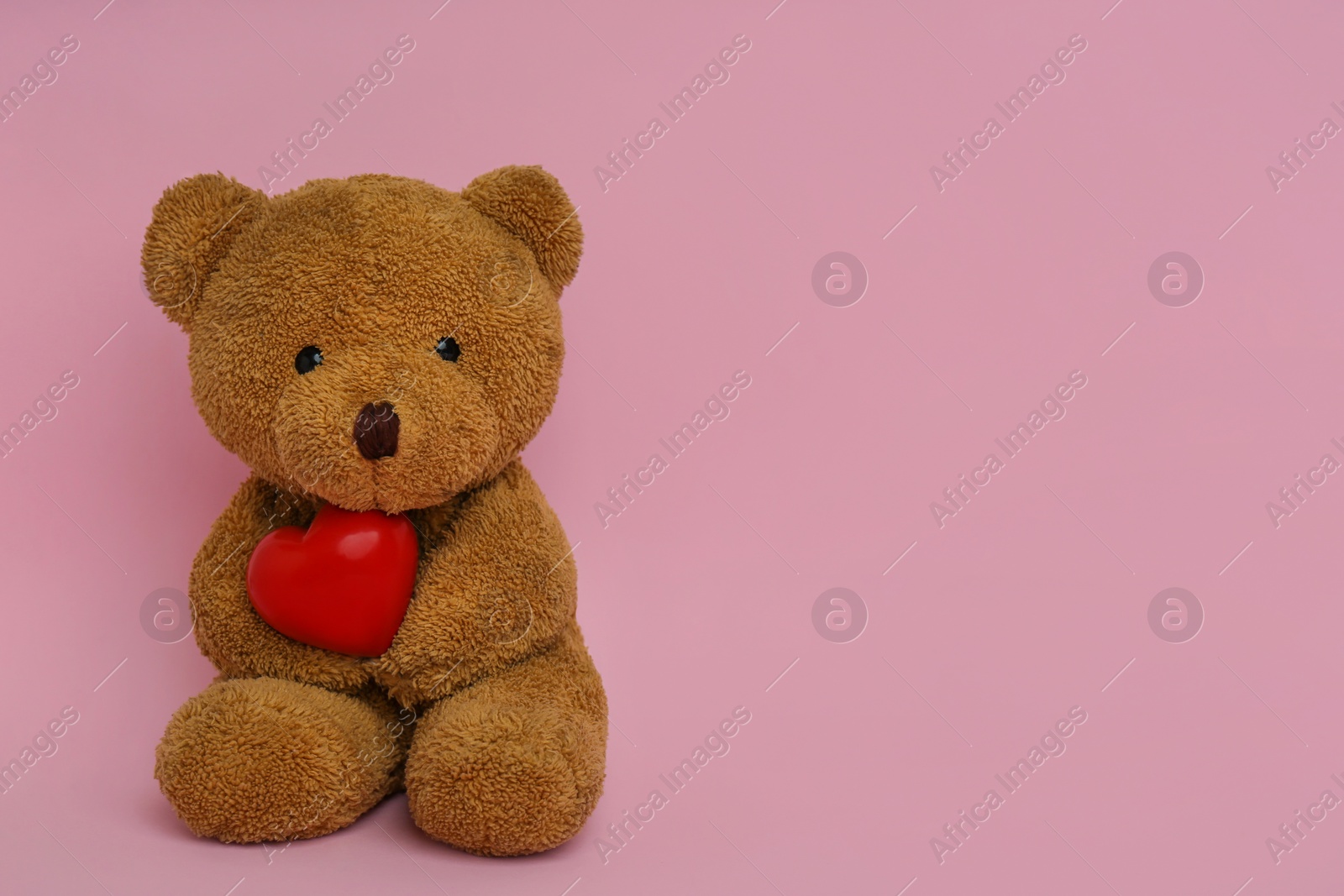 Photo of Cute teddy bear with red heart on pink background, space for text. Valentine's day celebration
