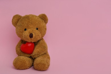 Photo of Cute teddy bear with red heart on pink background, space for text. Valentine's day celebration