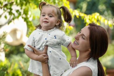 Happy mother with her cute daughter spending time together in park