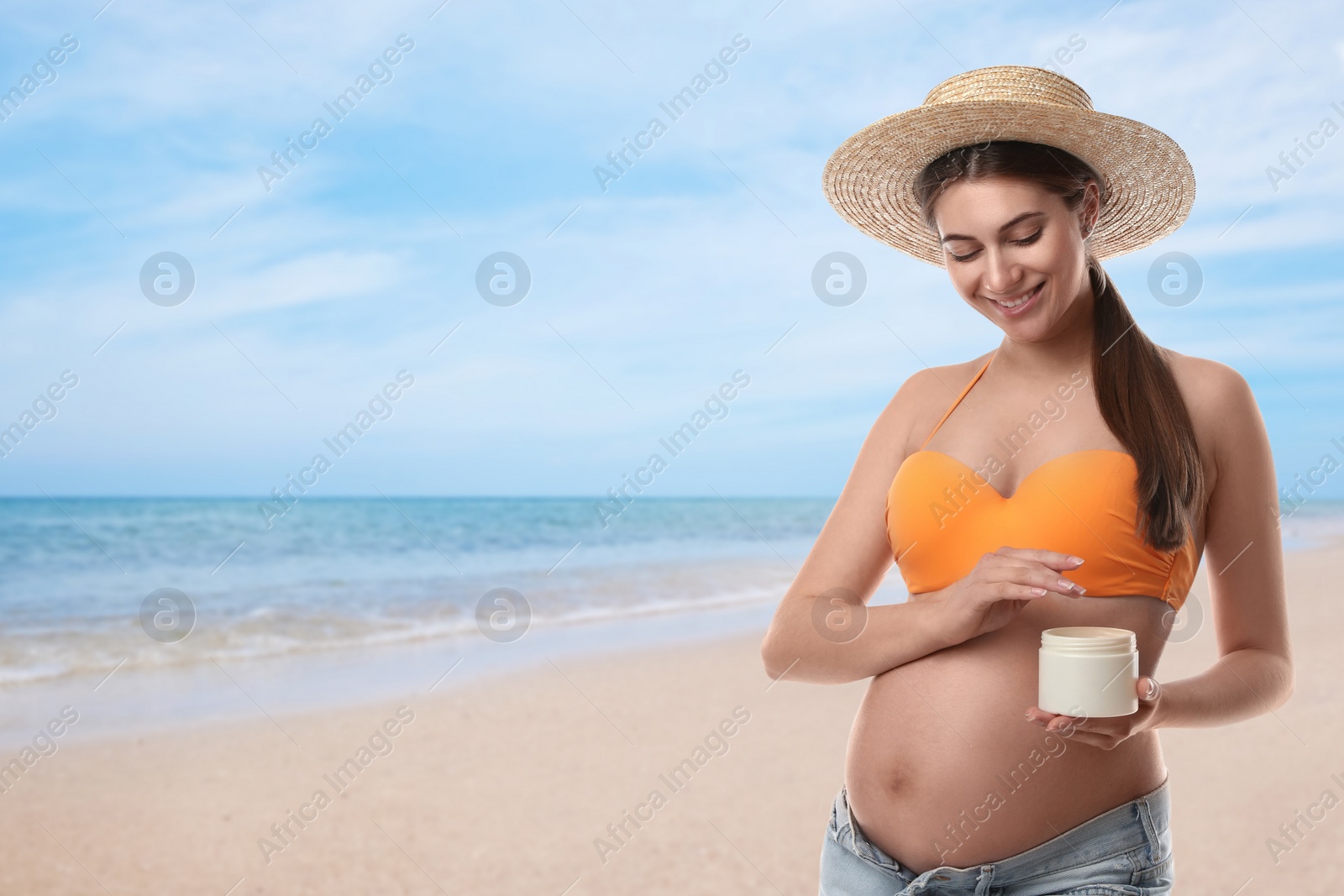 Image of Young pregnant woman with sun protection cream on beach. Space for text