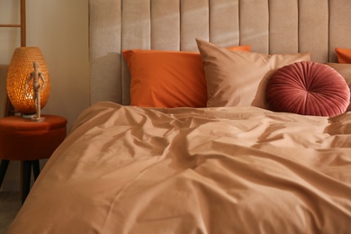 Bed with brown linen and different pillows in room