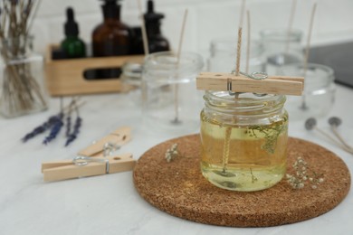 Photo of Glass jar with melted wax on white table, space for text. Handmade candle
