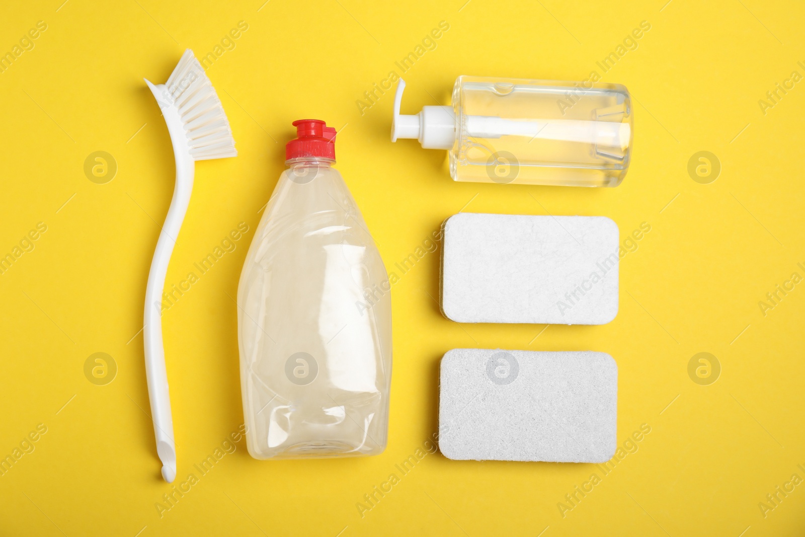 Photo of Cleaning supplies for dish washing on yellow background, flat lay