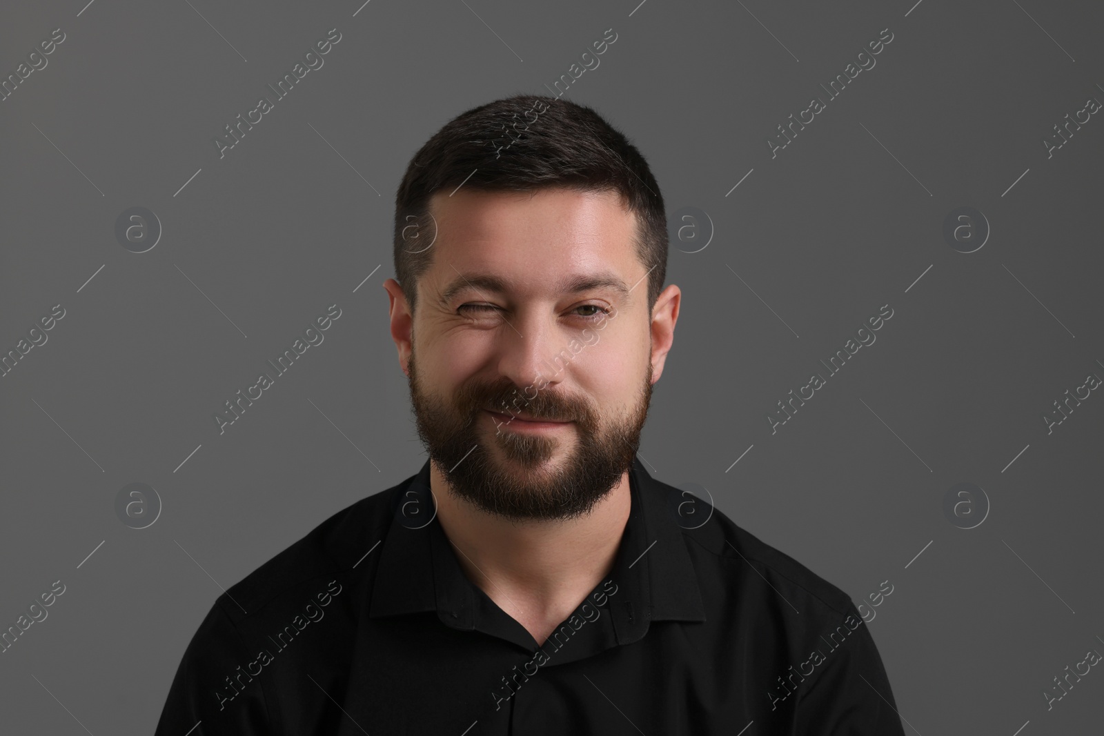 Photo of Personality concept. Handsome man winking on grey background