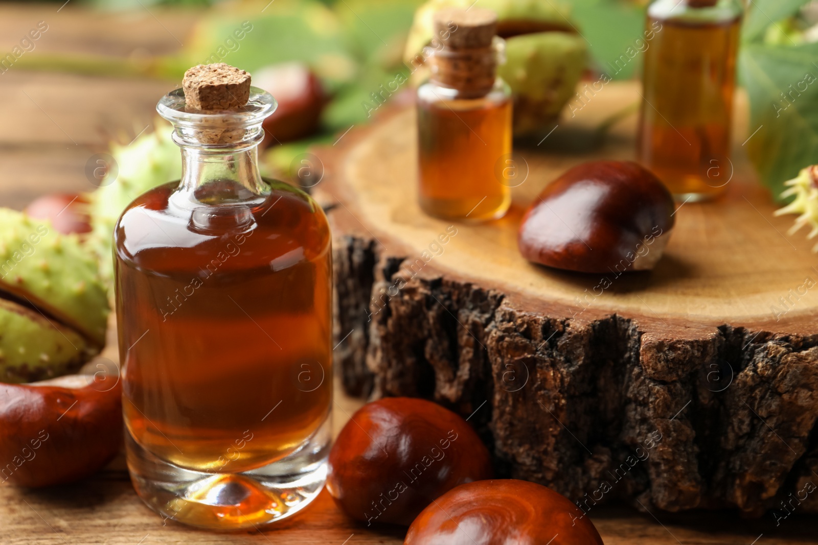 Photo of Chestnuts and bottles of essential oil on wooden table, closeup