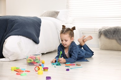 Photo of Cute little girl playing on warm floor at home. Heating system