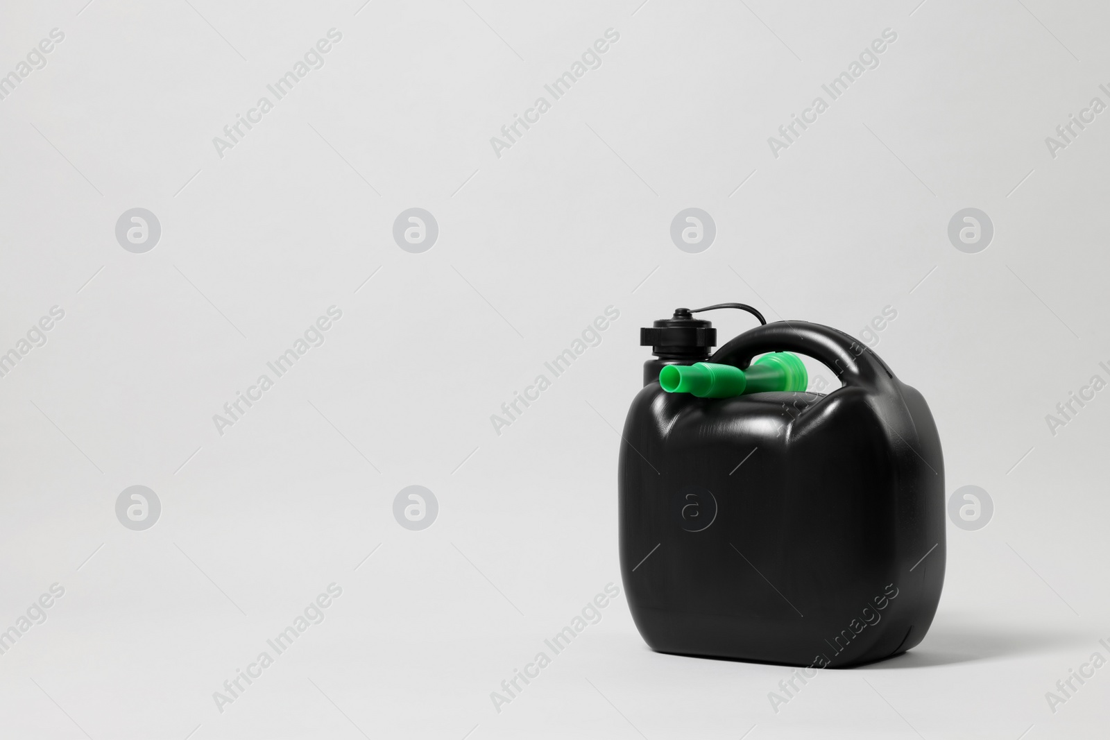 Photo of Black plastic canister with nozzle on light grey background. Space for text