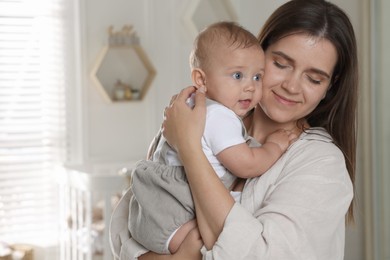 Photo of Happy young mother with her baby in nursery. Space for text