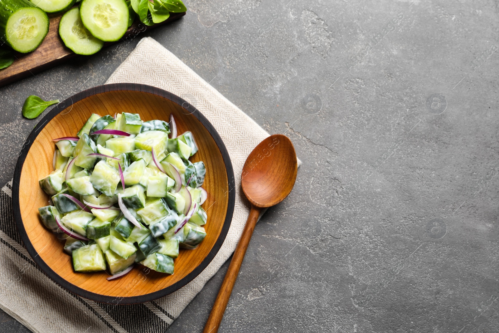 Photo of Flat lay composition with wooden plate of creamy cucumber salad and space for text on table