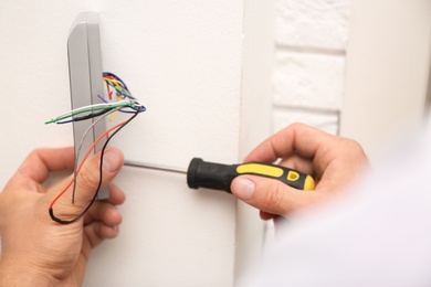 Photo of Male technician installing security alarm system indoors, closeup
