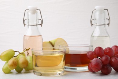 Photo of Different types of vinegar and ingredients on light table, closeup