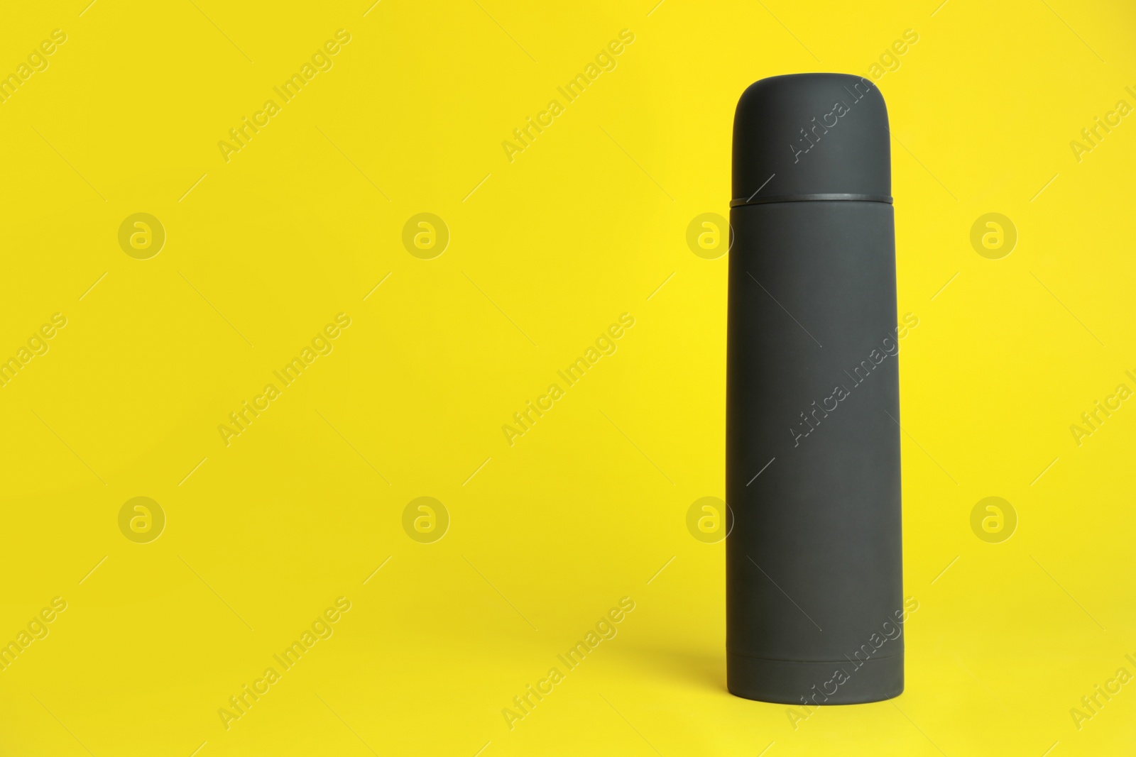 Photo of Stylish thermo bottle on yellow background, space for text