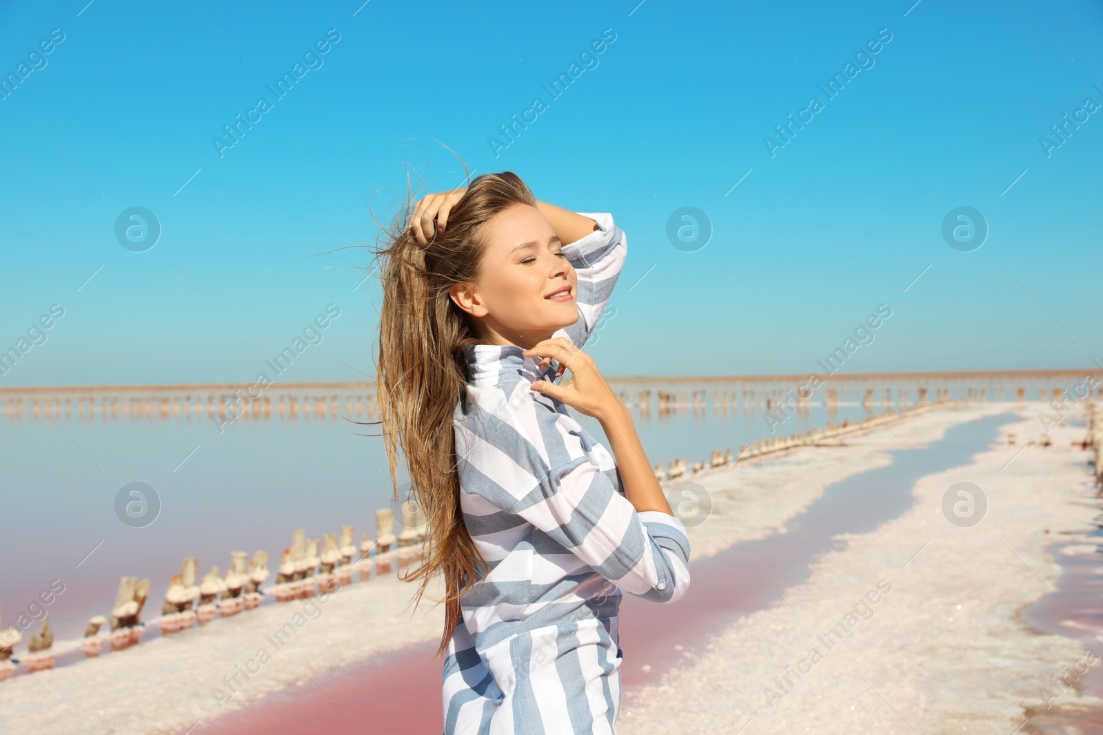 Photo of Beautiful woman posing near pink lake on summer day