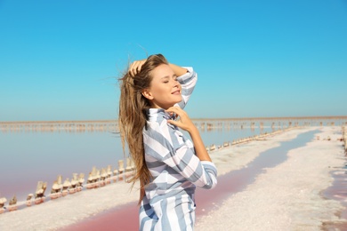 Photo of Beautiful woman posing near pink lake on summer day