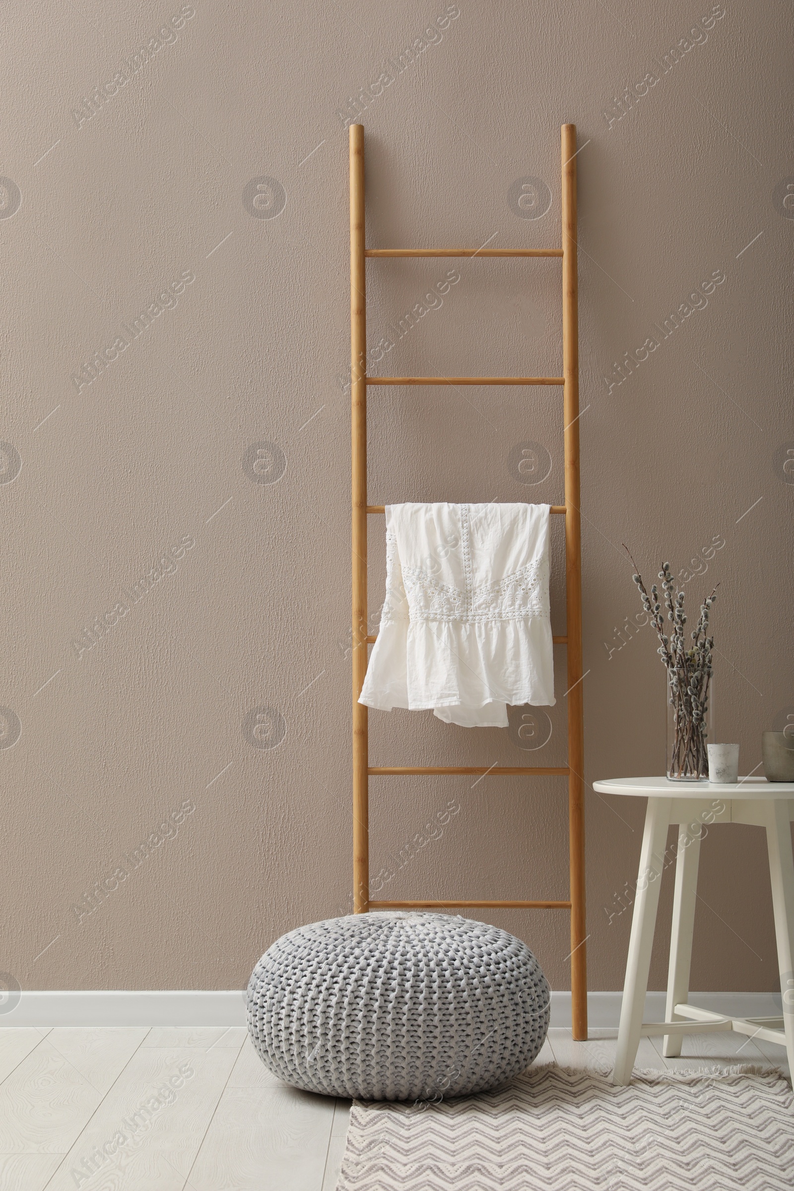 Photo of Stylish room interior with pouf, ladder and decor elements