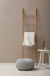 Photo of Stylish room interior with pouf, ladder and decor elements